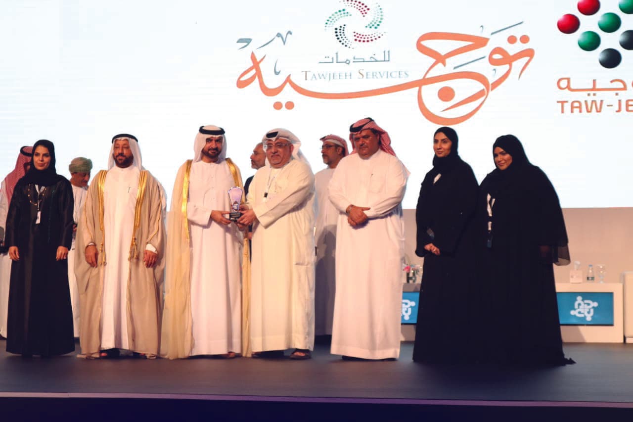 فريق توجيه للخدمات يتسلم جائزة تقدير الجودة على المسرح أمام شعار توجيه